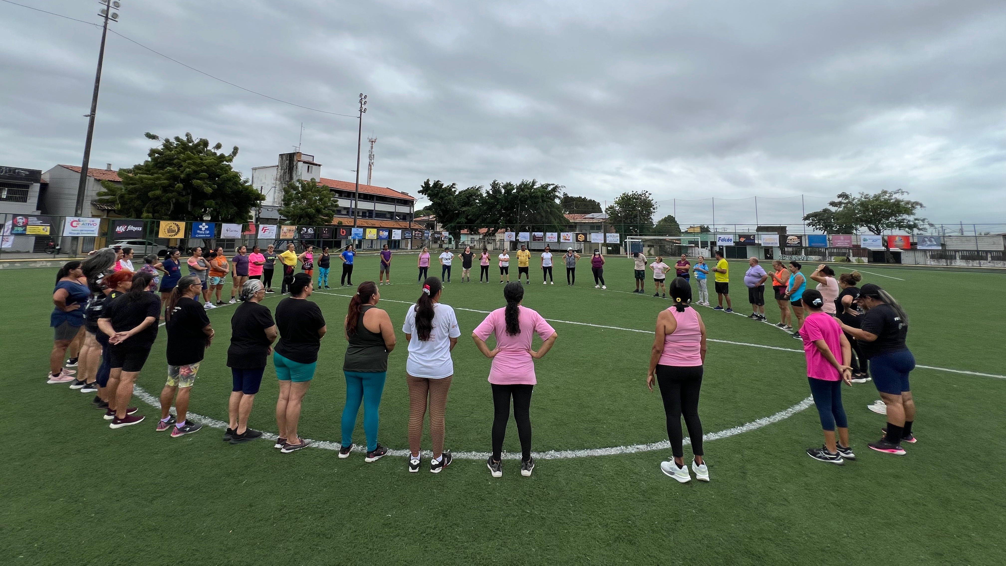 crianças formam um círculo no meio do gramado da Areninha